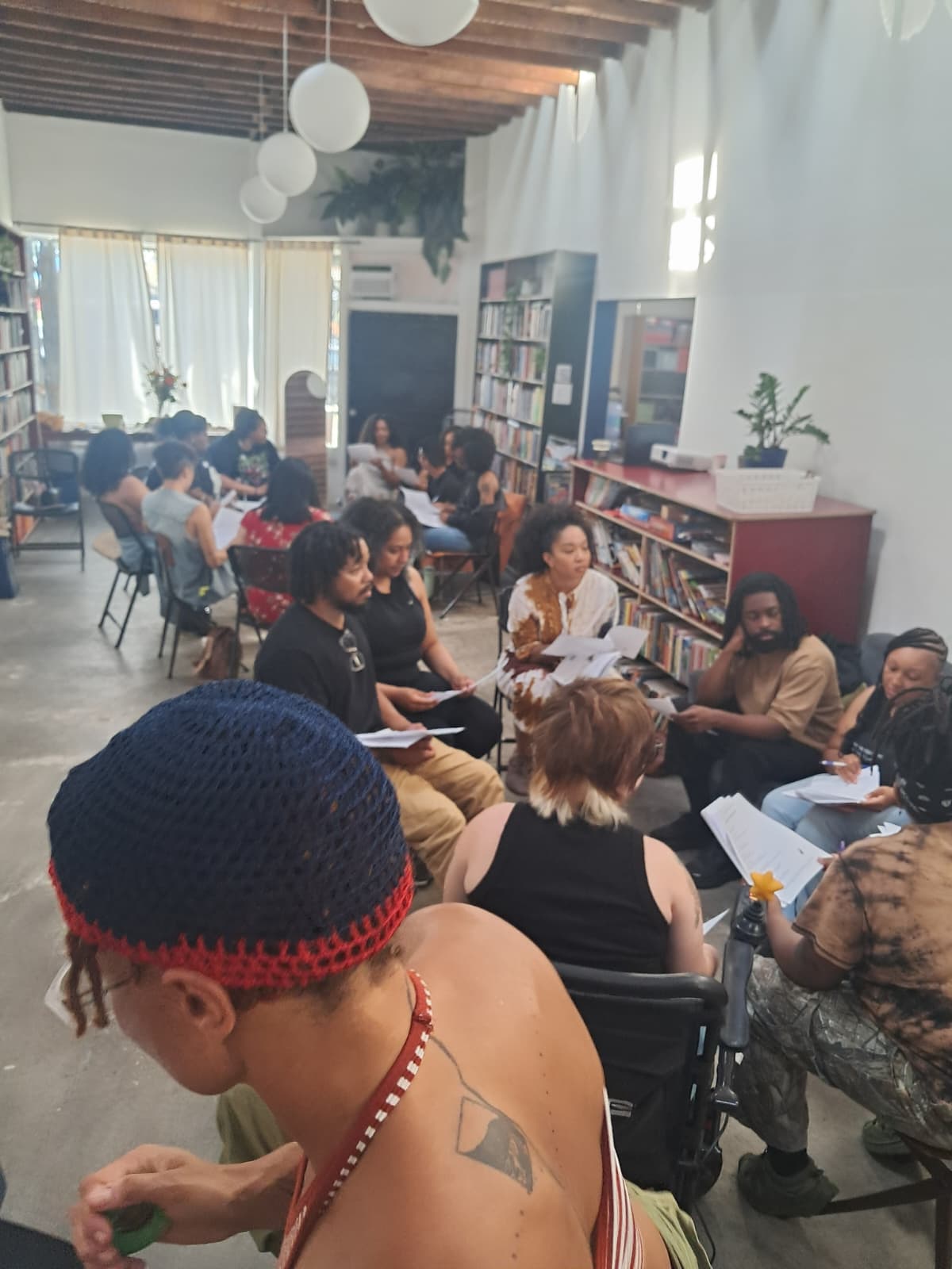 Participants in a small group circle practice discussing shared reflection notes in a community learning space.