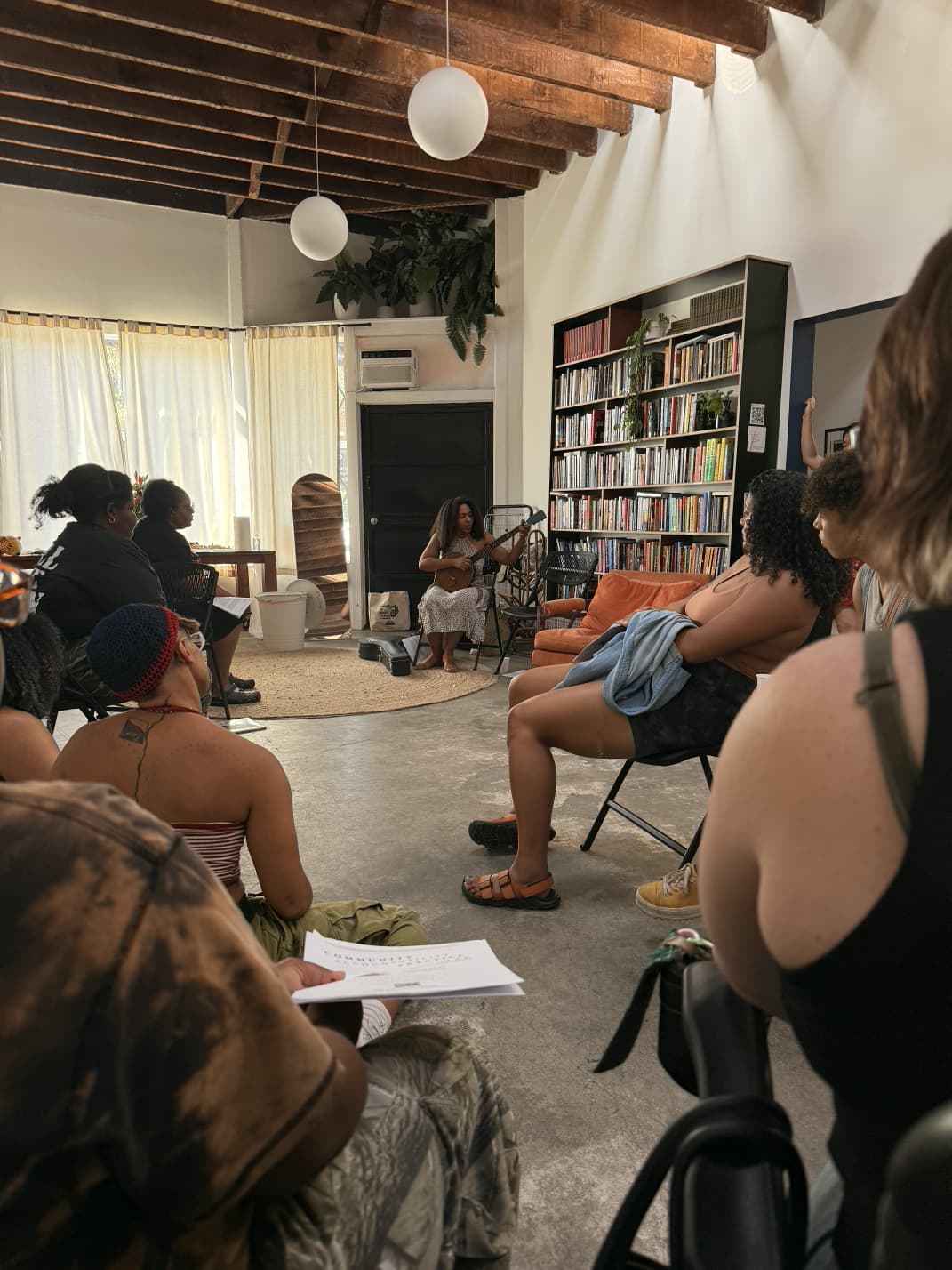 Facilitator leading a workshop with participants seated in a community space focused on collaborative learning.